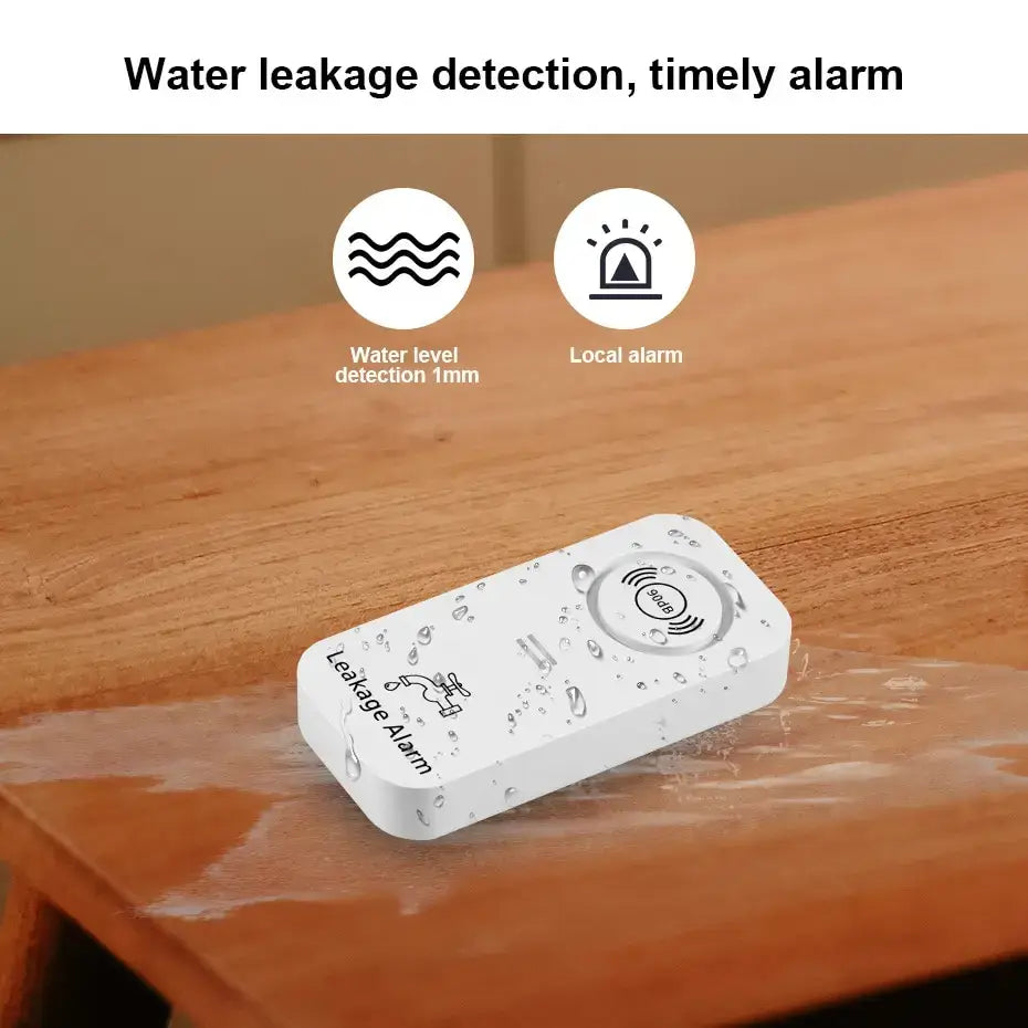 Wireless water leak sensor on a wooden surface detecting water; features 1mm detection and loud local alarm.