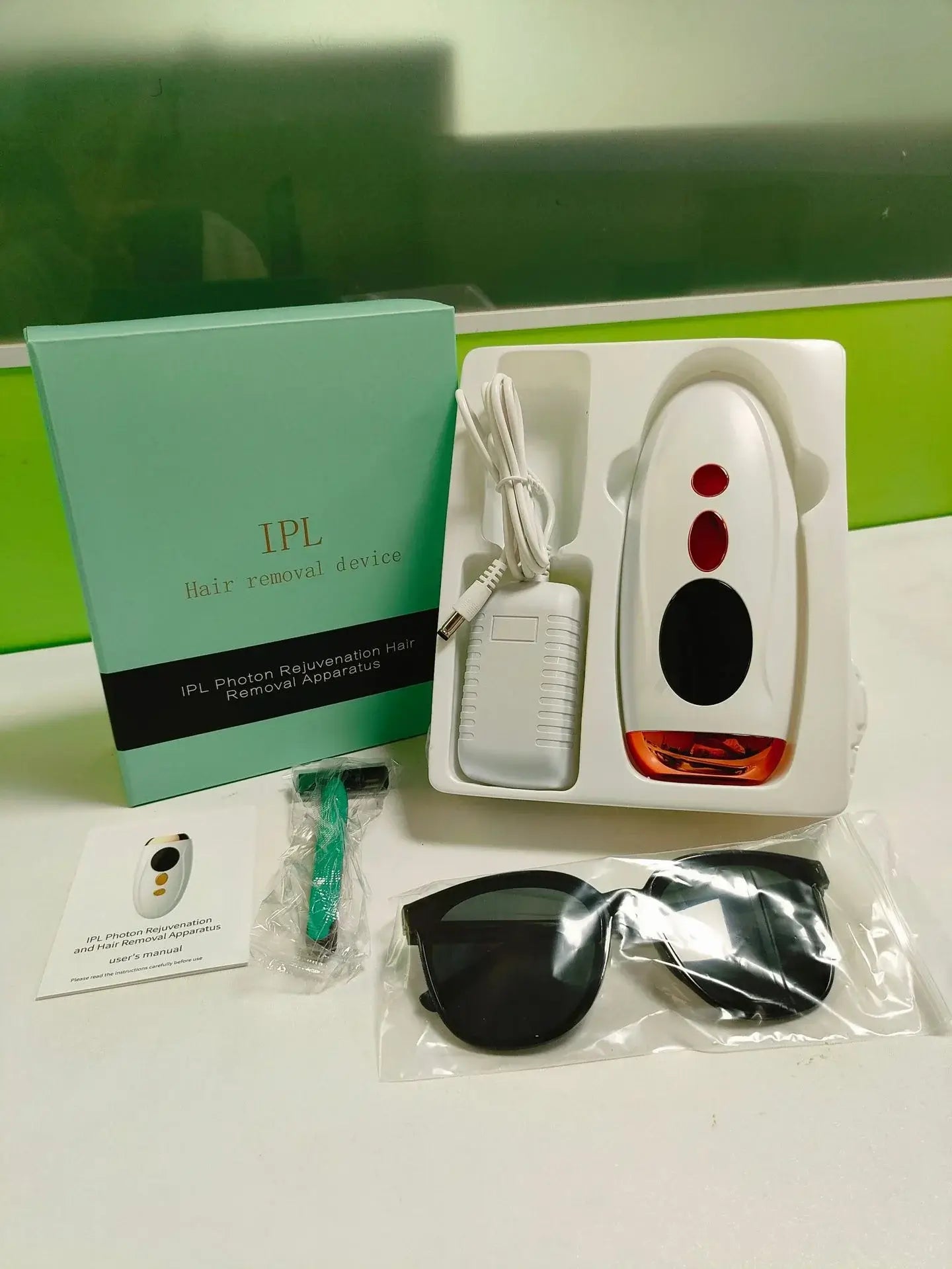 GlowSilk IPL Laser Hair Removal Device kit with sunglasses, manual, and accessories for home use.