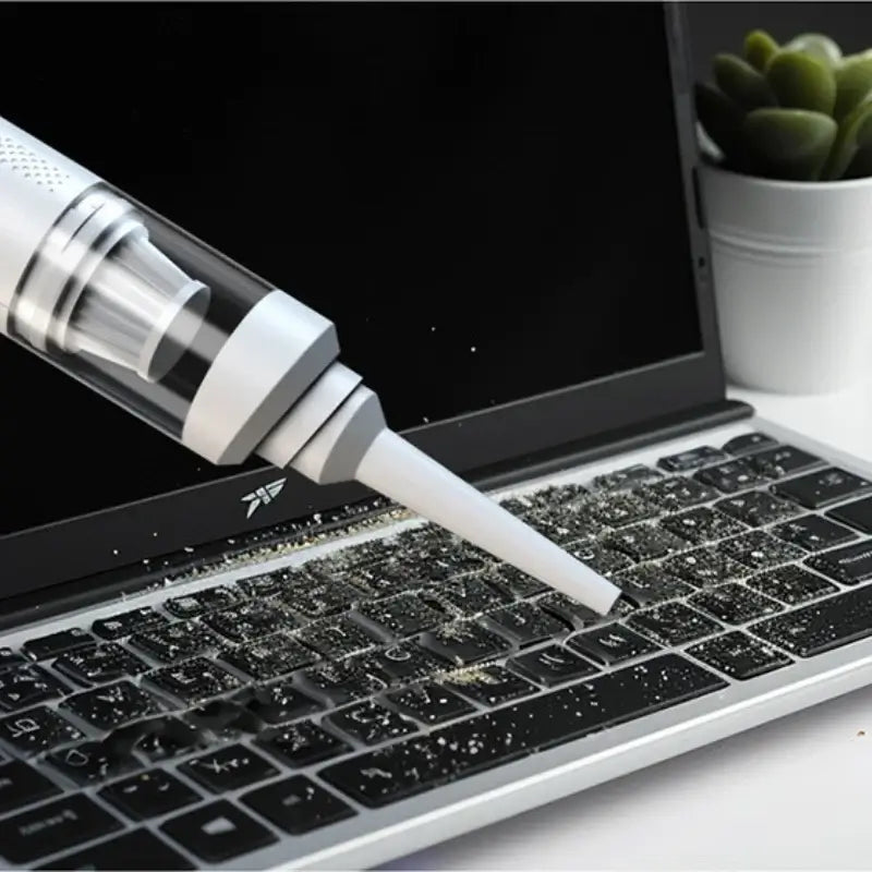 AeroVac One portable car vacuum cleaner removing dust from a laptop keyboard.
